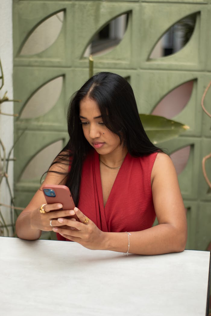 Home Woman in a red dress engaging with a smartphone, indoors. Modern lifestyle and communication.