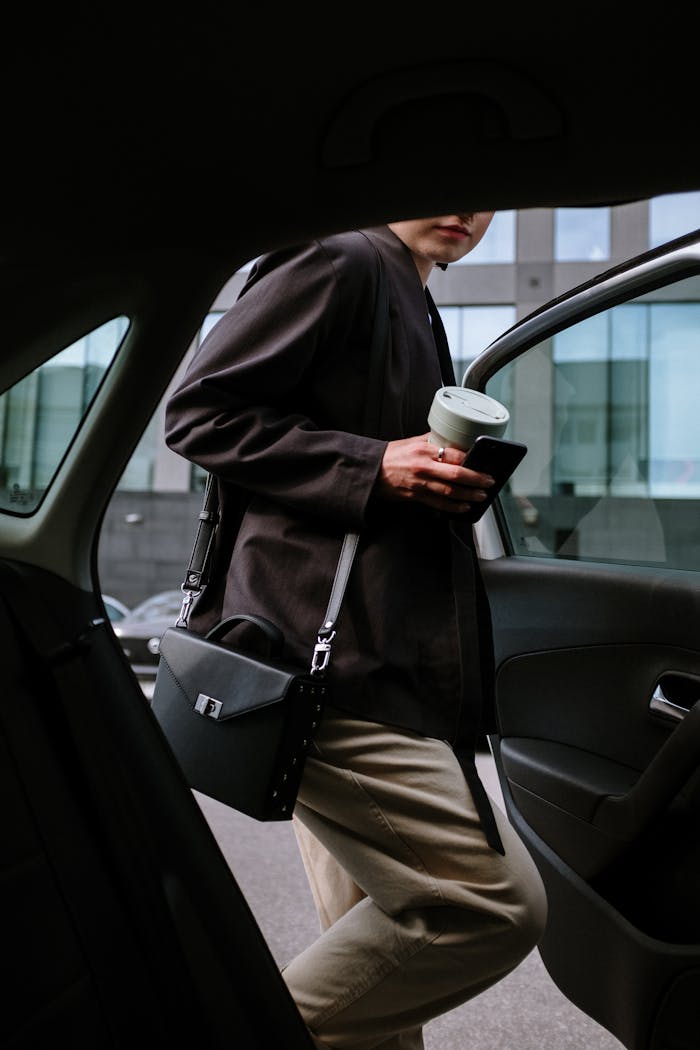 Portfolio Stylish woman entering a car, holding coffee and smartphone, showcasing urban lifestyle.