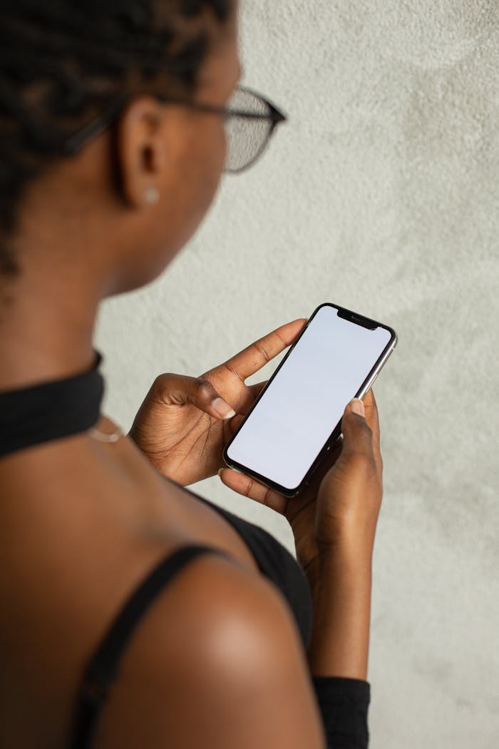 Crafting Captivating Headlines: Your awesome post title goes here Back view of woman holding smartphone with blank screen, ideal for app mockups or design presentations.